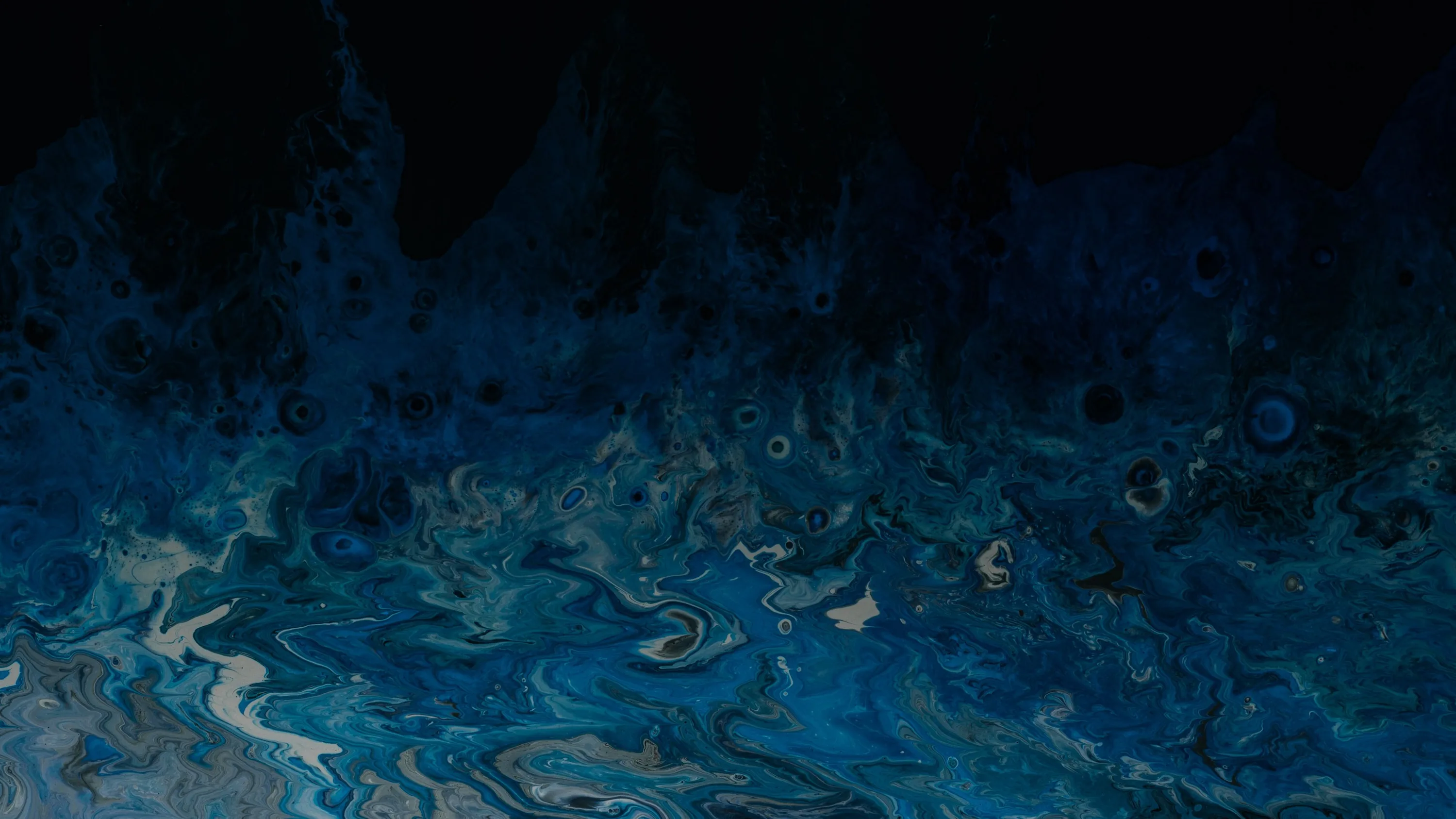 Poured acrylic in navy and teal swirls along the bottom half of the frame, the paint thinning into deep black toward the top edge.