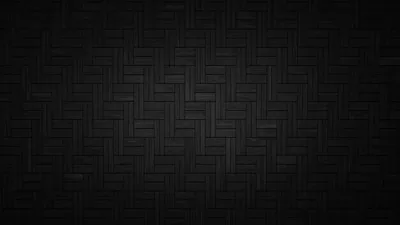 Charcoal tiles laid in a herringbone weave, a soft pool of light in the middle fading out to black corners.