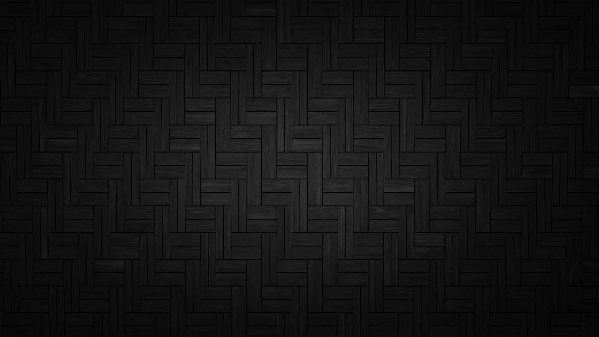 Charcoal tiles laid in a herringbone weave, a soft pool of light in the middle fading out to black corners.