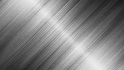 Fine brushed streaks angle across bright silver, the glare strongest toward the upper right while the left side settles into mid grey.