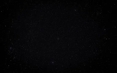 A grainy star field with a pale glow along the left edge and a slight vignette, most of the frame reading as flat black.