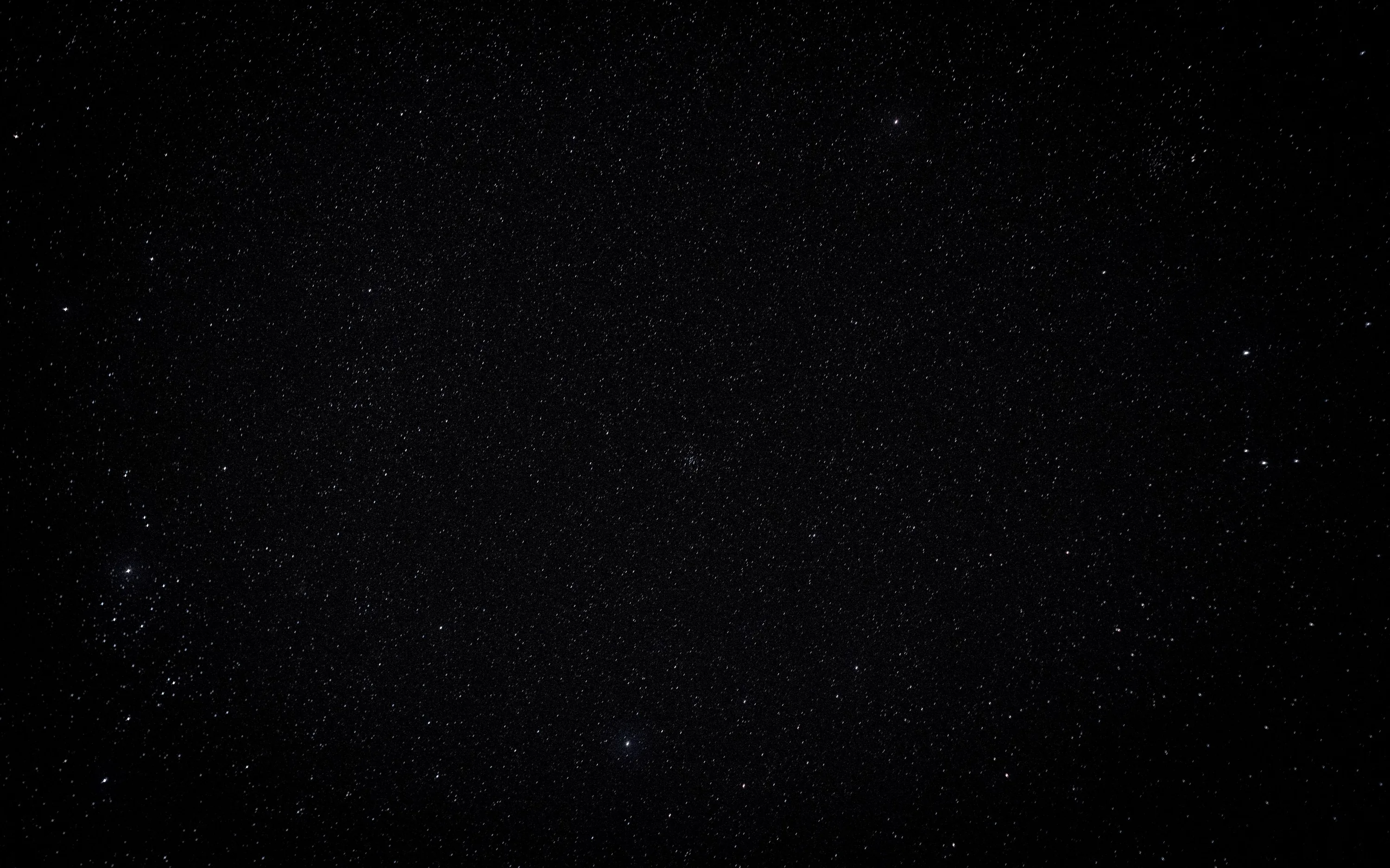 A grainy star field with a pale glow along the left edge and a slight vignette, most of the frame reading as flat black.
