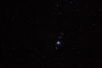 One star flares just right of centre while hundreds of faint pinpoints fill the rest of a near-black night photo.