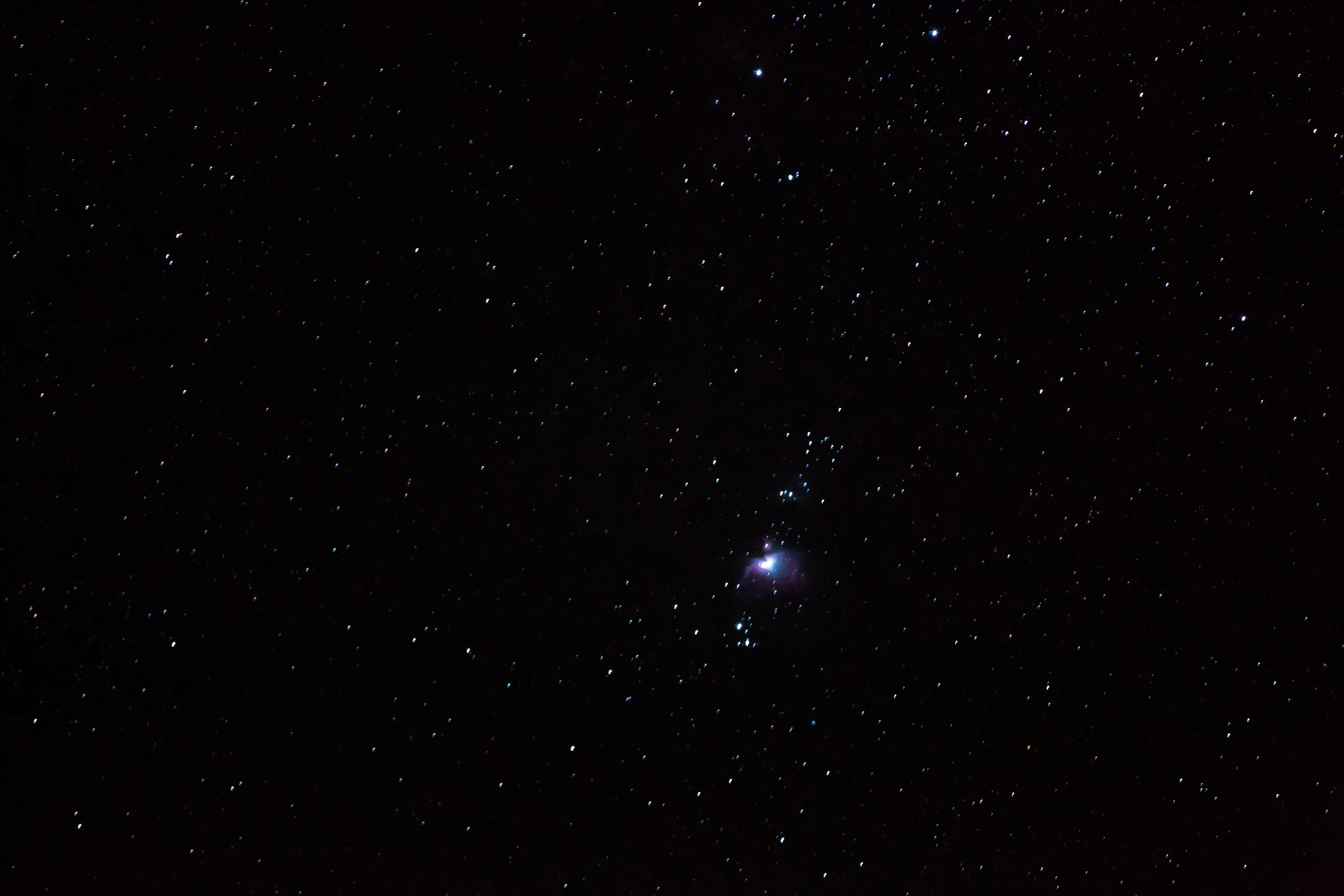 One star flares just right of centre while hundreds of faint pinpoints fill the rest of a near-black night photo.