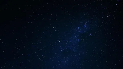 A soft blue haze of unresolved stars runs down the right of the frame, the left side dropping off into near-black.