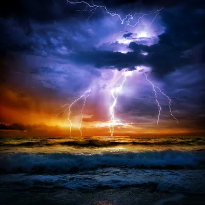 Three bolts strike the sea at once behind a breaking wave, sunset burning orange along the left edge of the storm.