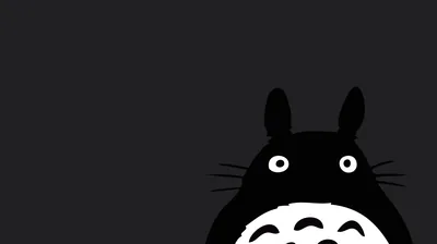 Totoro rises into the lower right corner against flat charcoal, wide eyes and whiskers the only detail, the rest of the frame left empty.