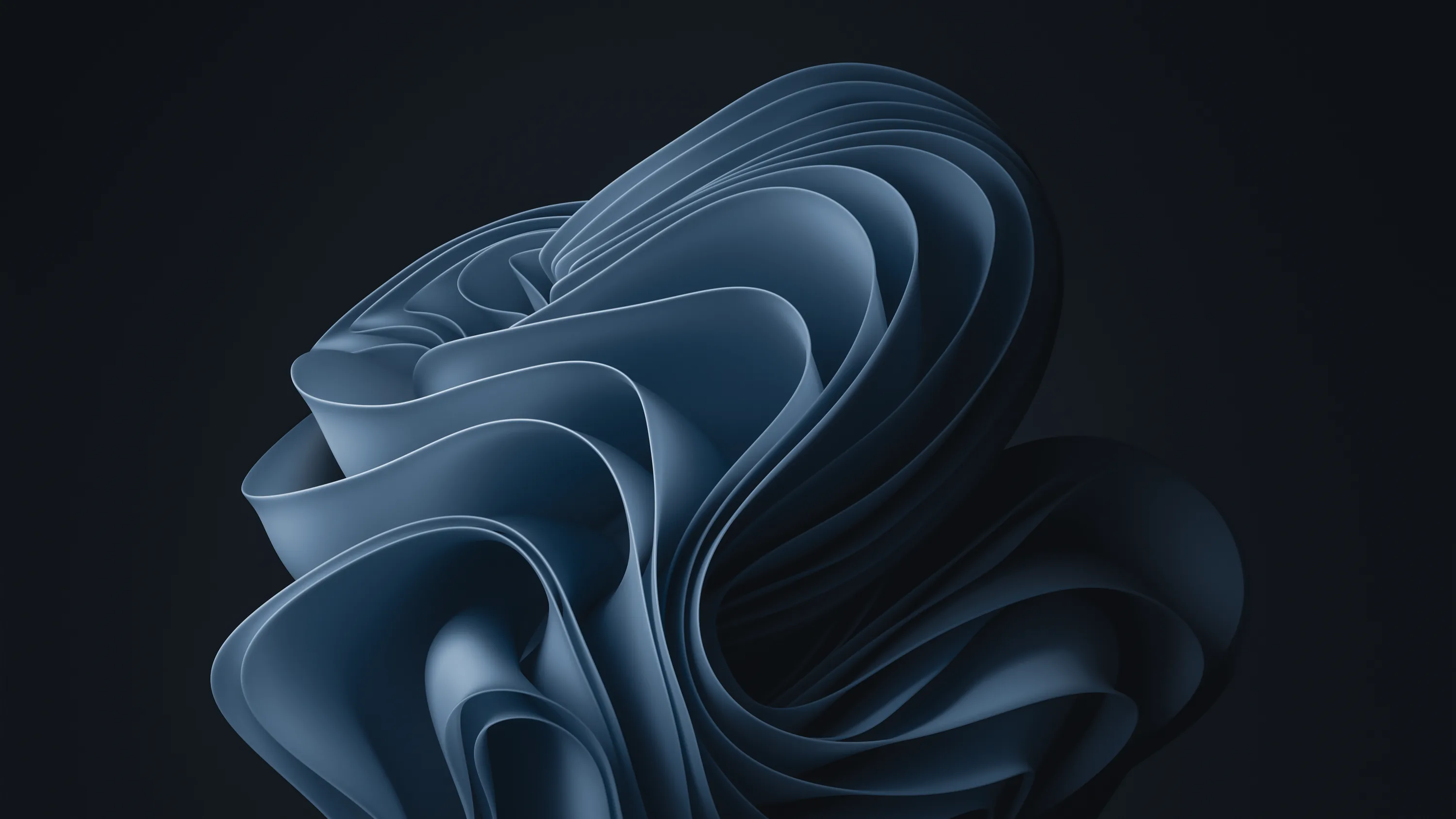 The layered bloom shape of Windows 11 curls in on itself in cool blue-grey, set against a near-black backdrop with the left third left empty.