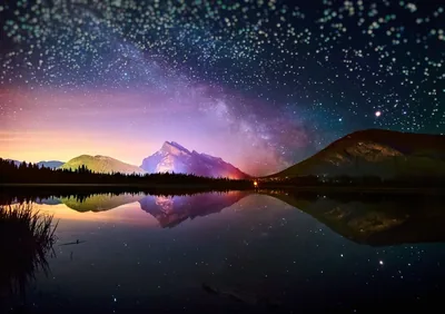 A purple-and-teal starfield doubles in a glassy mountain lake, the mirrored peak sitting dead centre so the image survives a square crop.