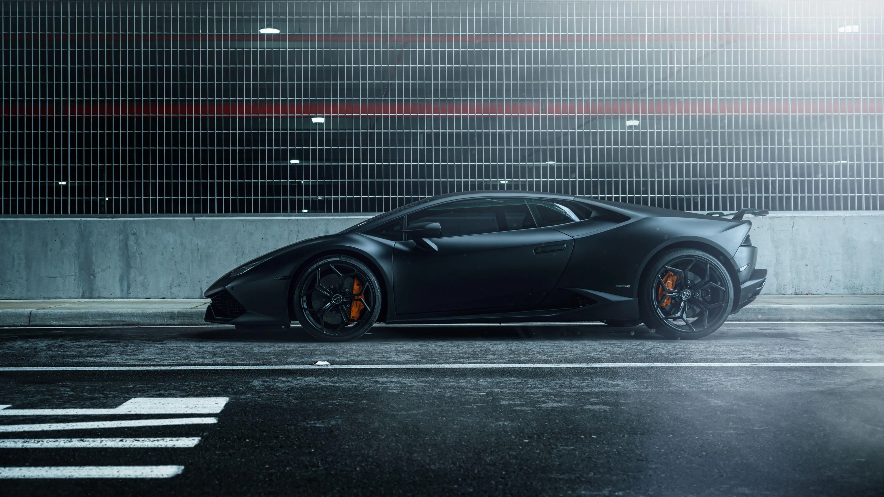 The car sits dead side-on against a corrugated metal wall lit by a single red strip, road markings and a kerb running along the bottom of the frame.