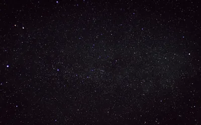 The Milky Way runs diagonally through a dense star field, its dust lanes visible as darker patches against the packed white points.