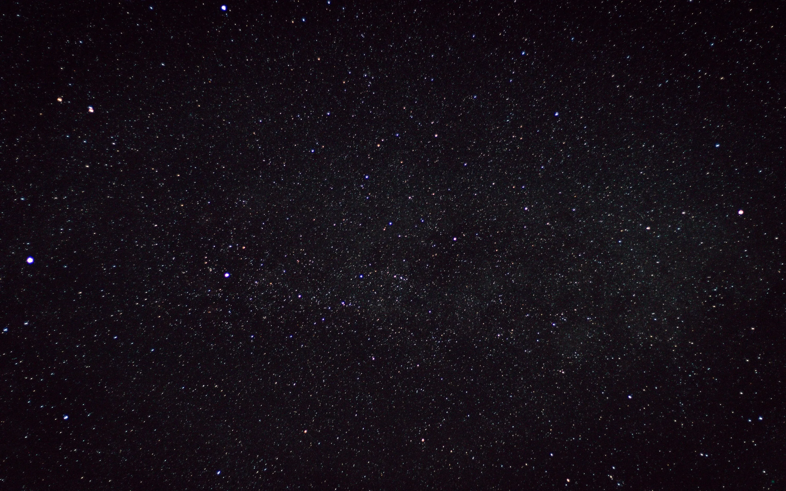 The Milky Way runs diagonally through a dense star field, its dust lanes visible as darker patches against the packed white points.