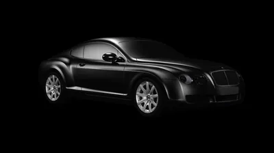 Studio lighting skims the shoulder line of a black Bentley coupe, the rest of the body sinking into a seamless black field with no floor visible.