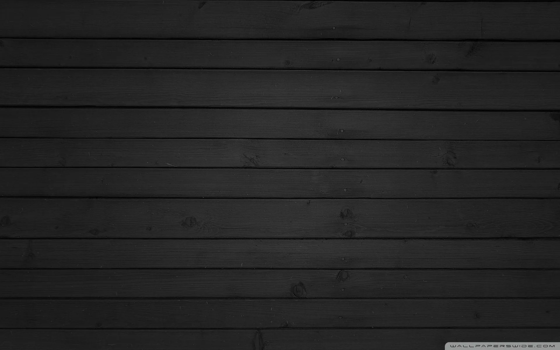 Wide planks run edge to edge in charcoal grey, grain and knots showing where the light crosses the middle rows.