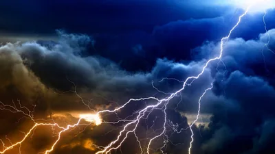Several bolts tear through a churning sky at once, orange light breaking in from the left while the right side stays storm-blue.