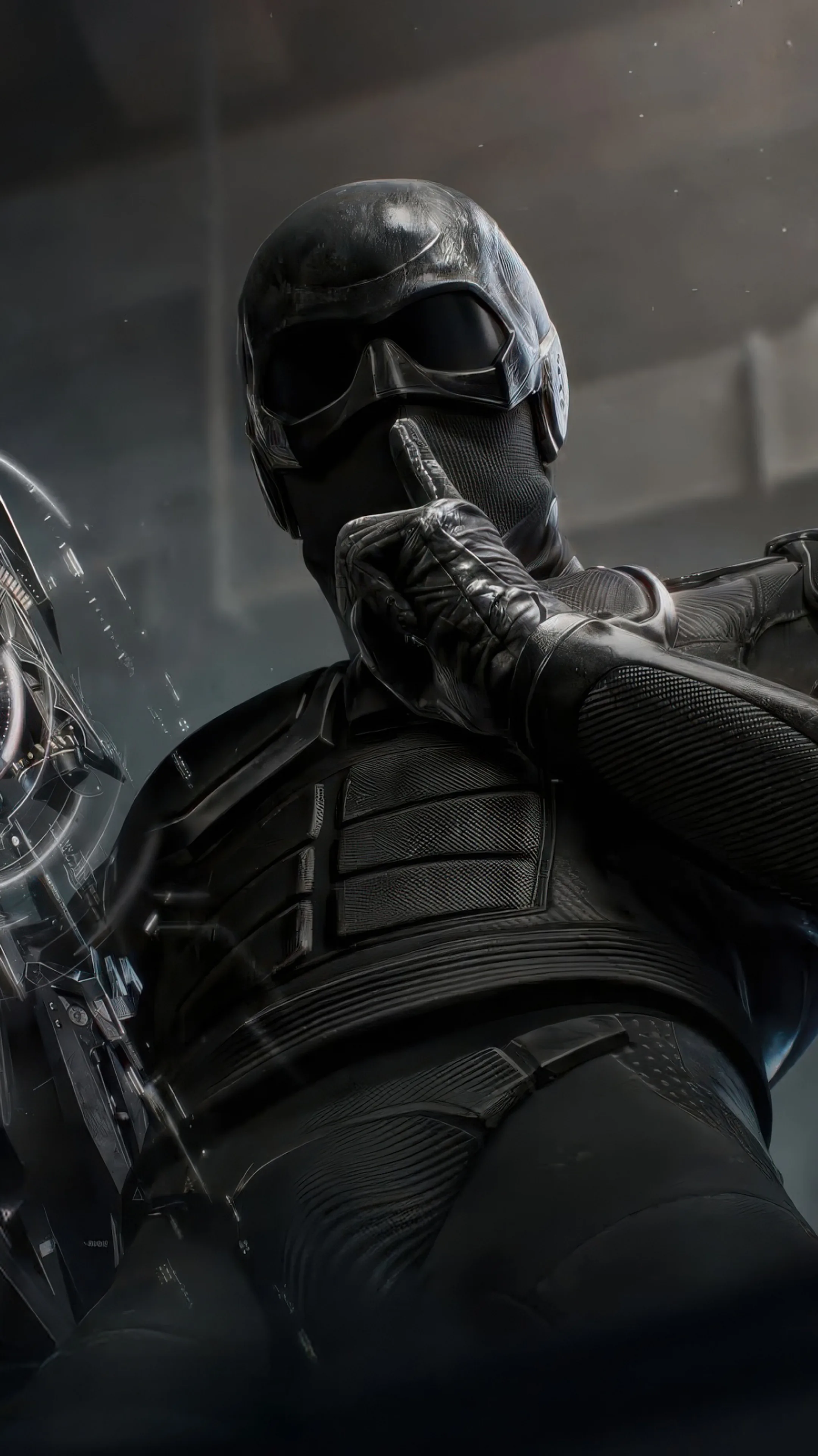 The masked figure crouches in matte black body armour with a blade drawn, goggles catching the only light in a grey concrete room.