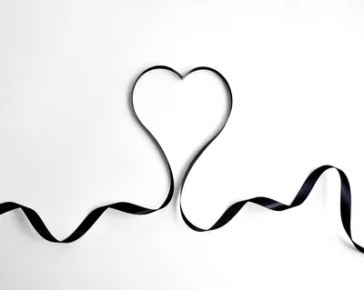 A black ribbon loops up from both lower corners and folds into a single heart just above centre, the white ground left clean on every side.