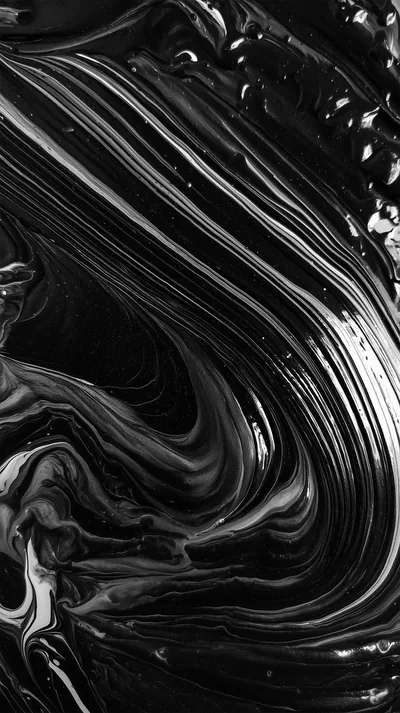 Thick black and white paint pulled into liquid ribbons, the glossy surface catching light along every ridge in this close-up texture.
