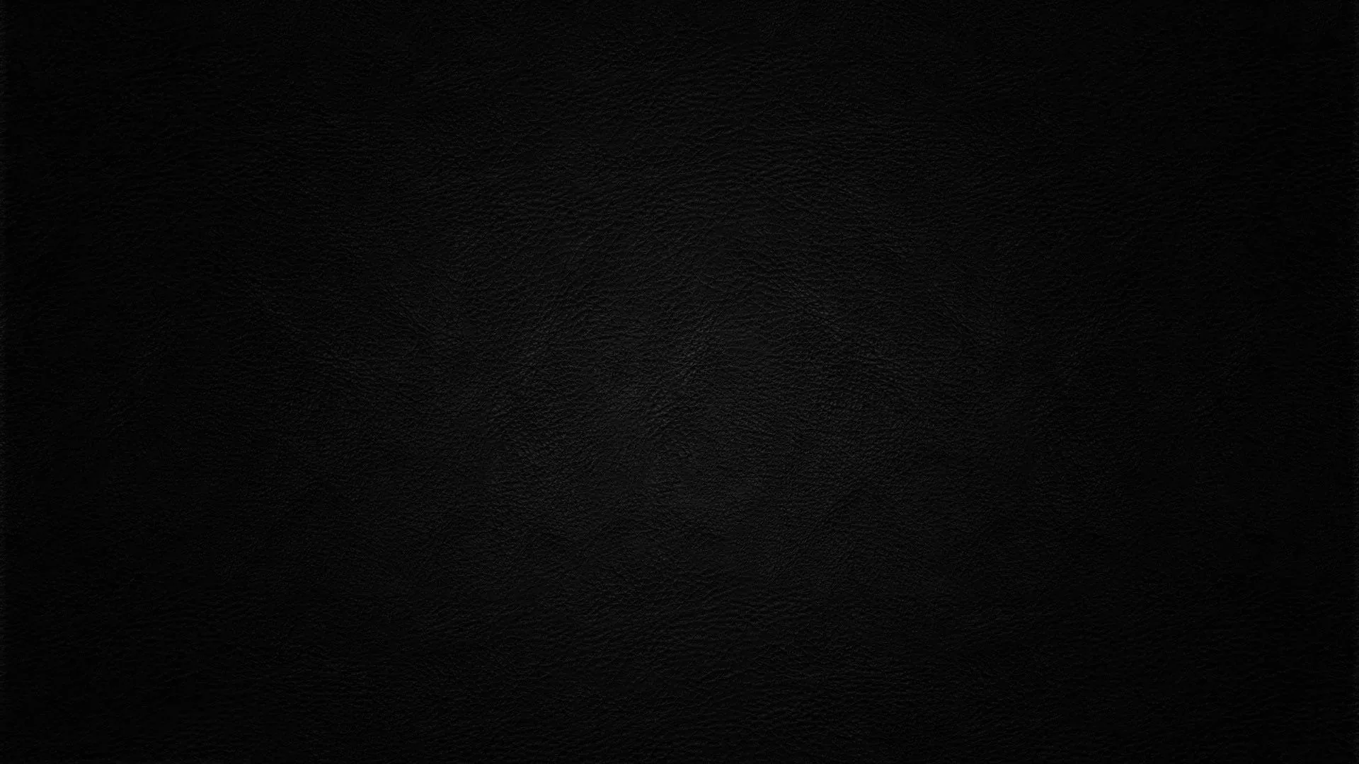 Almost the whole frame sits at true black, a faint circular grain surfacing near the middle before the corners fade out completely.