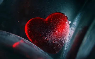A macro shot of an ice-crusted heart pressed behind curved glass, a faint red glow spilling into the lower left while the right edge stays cold grey.