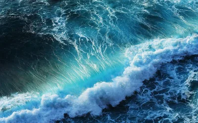 Foam boils along a breaking wave seen from above, veins of white lacing the darker water toward the top corners.