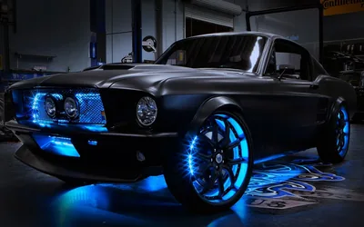 A custom fastback Mustang in a workshop, blue LEDs ringing the wheels and spilling across the floor under the sills.