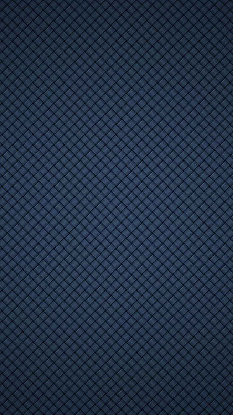 A tight quilted grid of diamonds in slate navy fills the frame edge to edge, lit slightly brighter through the centre than at the corners.