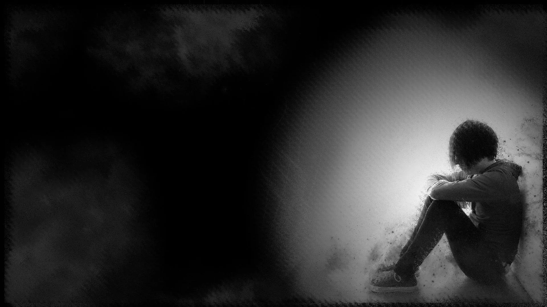 Pressed into the bright right edge of the frame, a boy hugs his knees while grain and smoke blur everything, the left half sinking to black.
