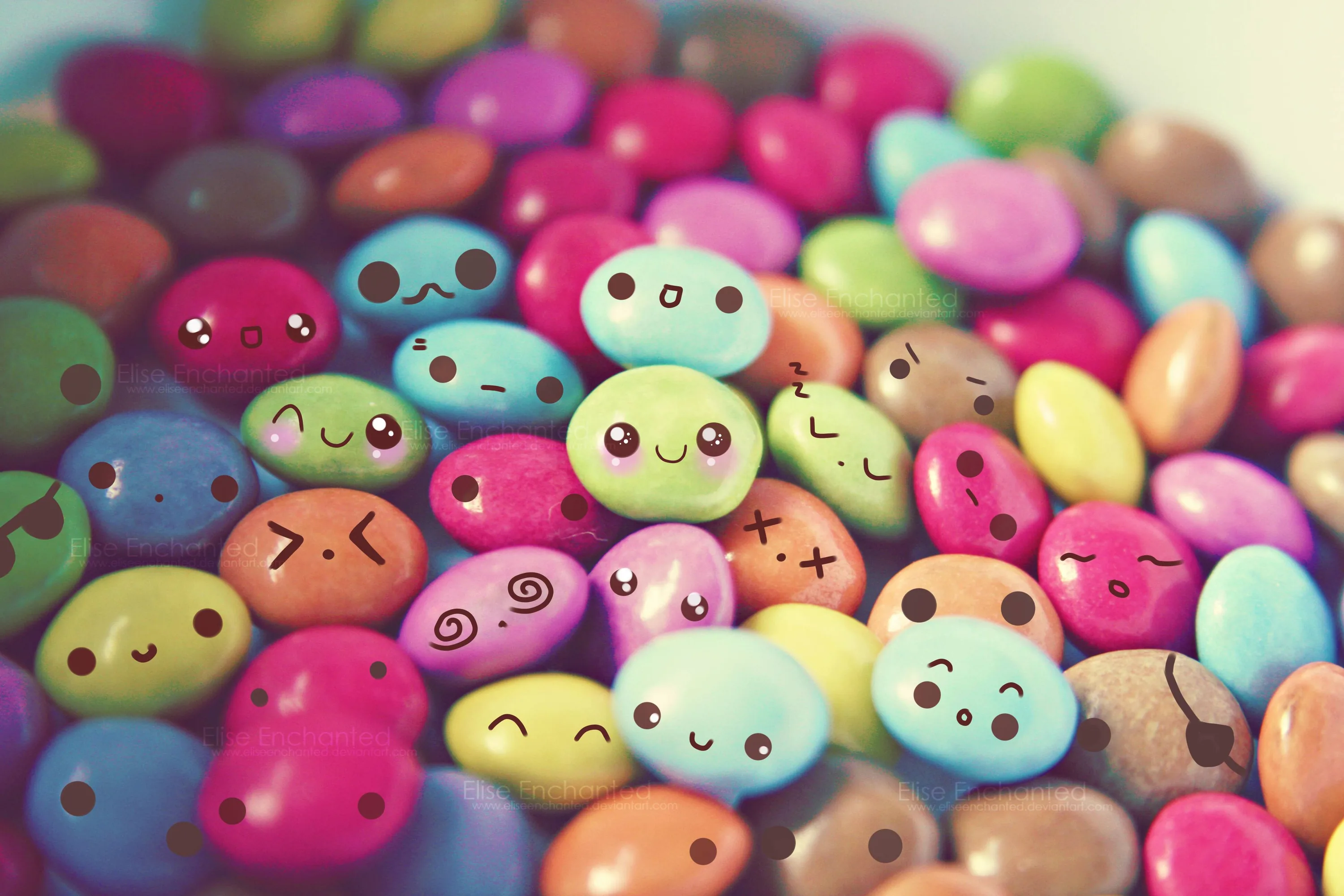 A macro photo of sugar coated chocolate buttons, each inked with a different expression; the shallow focus blurs the top rows into soft colour.