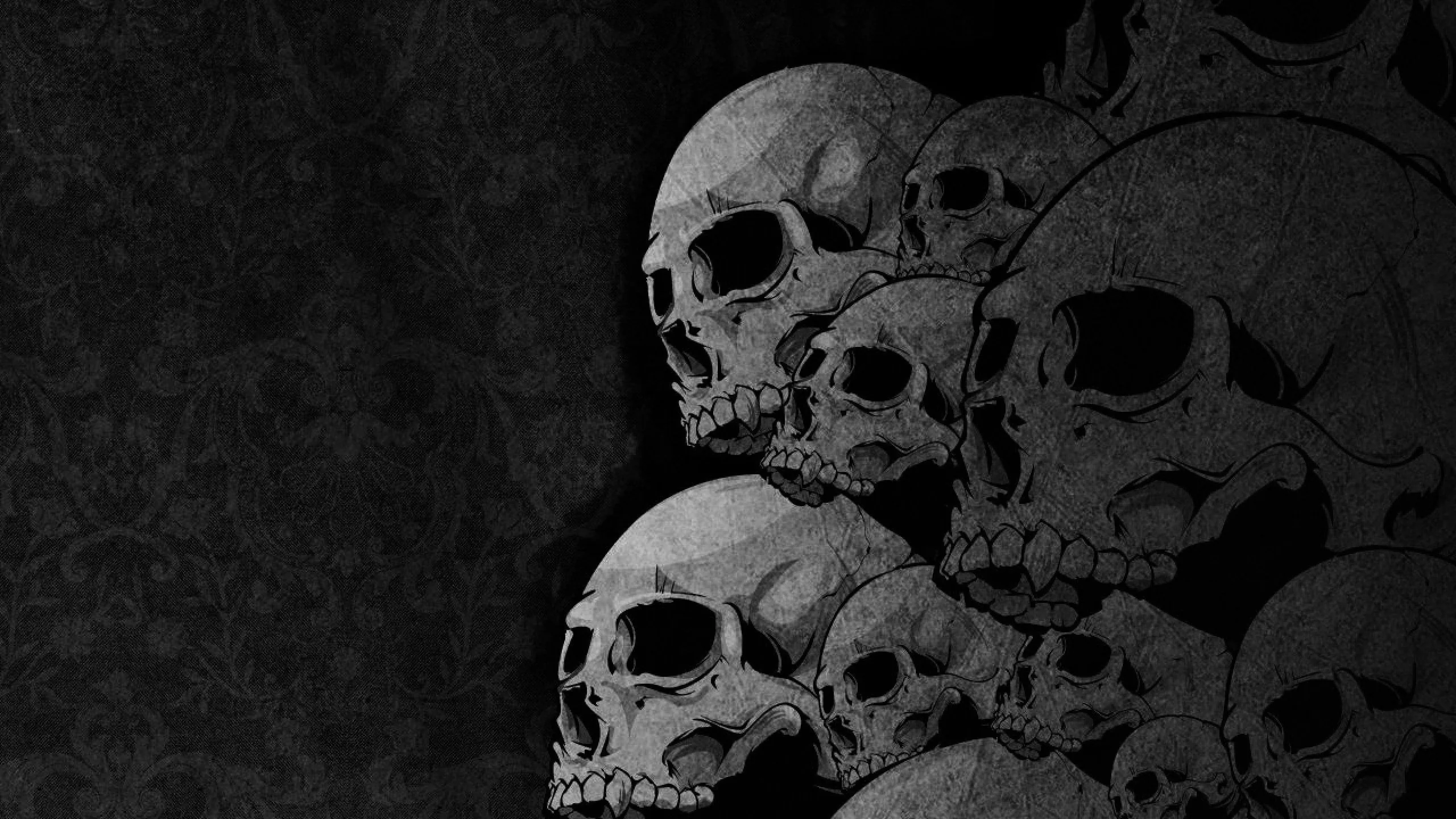 Five weathered skulls pile up along the right edge in front of a faint damask pattern, the left third left in near-total black.