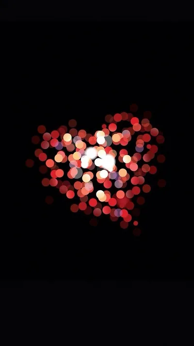 Dozens of out-of-focus red and white lights cluster into a heart, brightest at the core and fading into black at the edges.