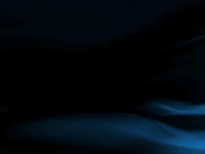 Almost the whole frame sits in black, a single soft fold of blue light surfacing along the bottom edge.