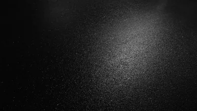 Fine grit sparkles under a beam raking in from the top, the bright band running through the middle left while every corner falls to black.