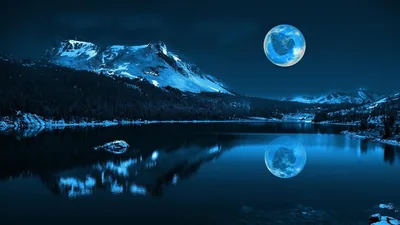 Snowy peaks and a blue moon repeat in the mirror-still water, the reflection filling the lower half so the sky stays clear for a desktop clock.