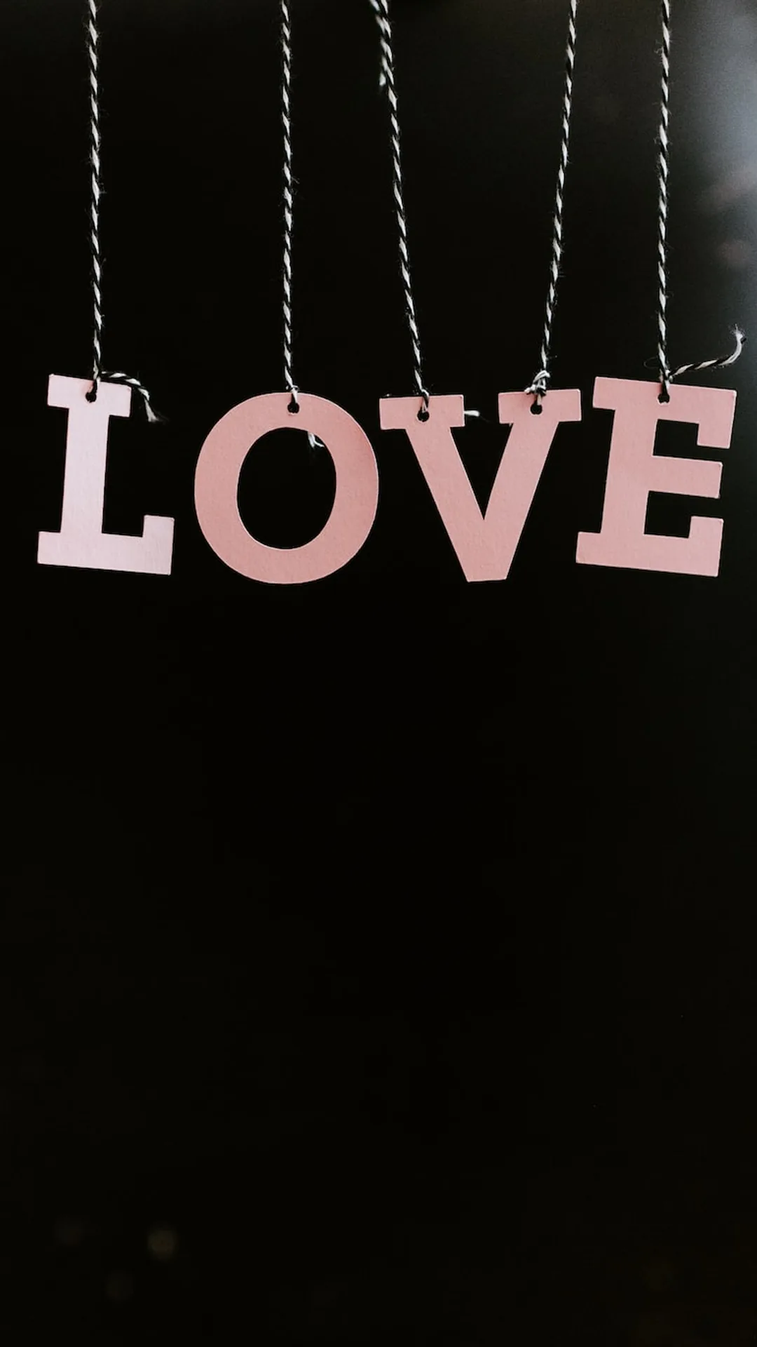 Four pale pink letters dangle from twisted cords across the upper half of a black background, leaving room below for icons.