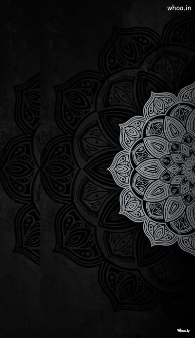 A half mandala in fine grey line work sits against a scuffed dark wall, its detail densest along the right edge.