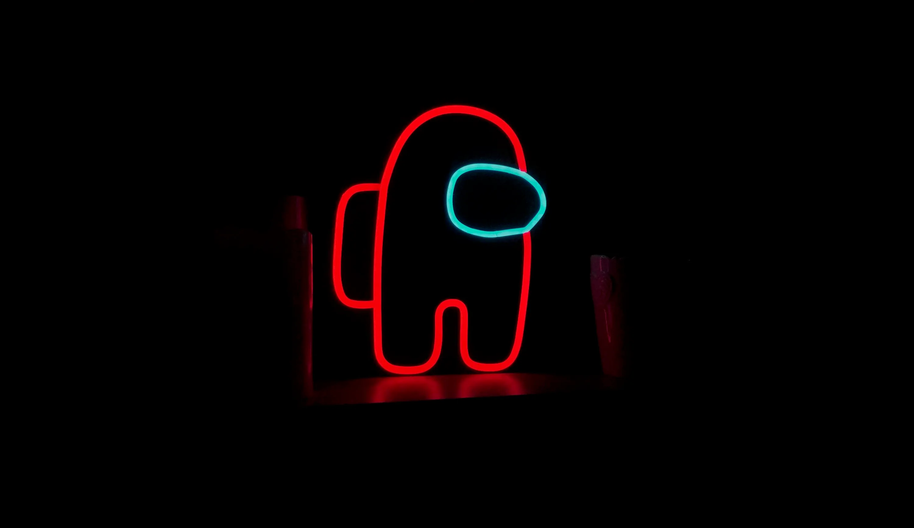 The Among Us crewmate shape glows red with a cyan visor, its light falling off fast into black on every side.
