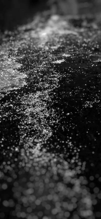 Macro shot of fine silver dust scattered over a black surface, the sparkle band running diagonally and falling out of focus at the bottom.