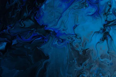 An acrylic pour in azure and ink black, brightest where the paint pools toward the upper right, darkest cells collecting in the left corner.