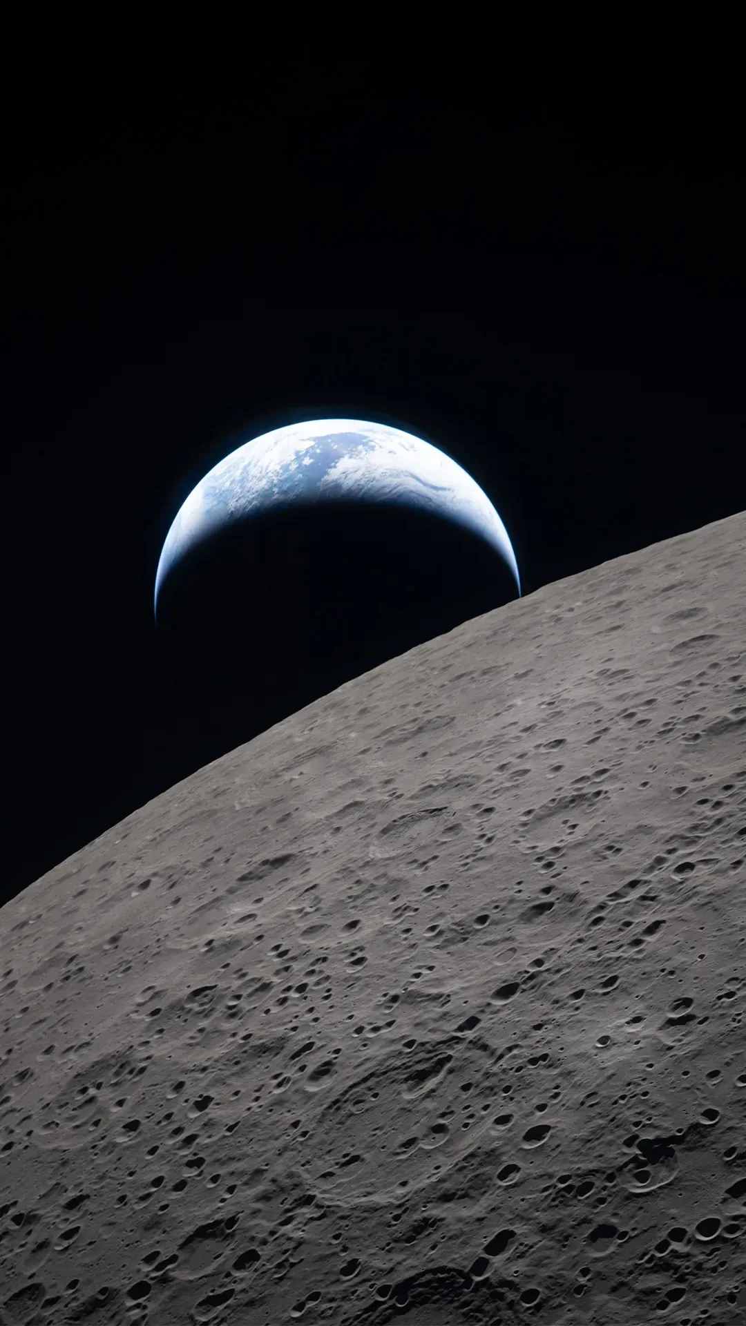 A crescent Earth hangs above the cratered grey curve of the Moon as seen from lunar orbit, deep black space filling the top of the frame.