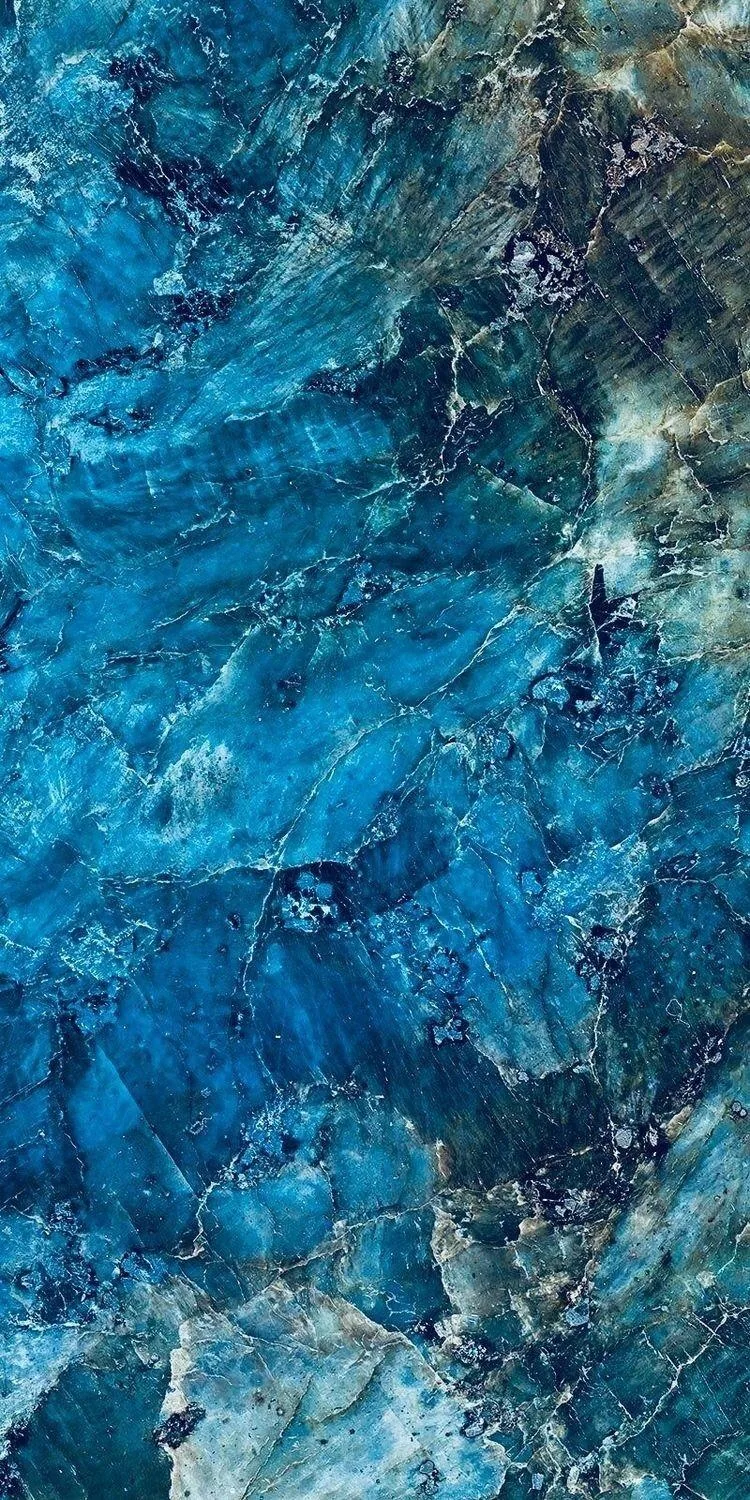 Vivid cobalt and turquoise crystal faces webbed with fine white fractures, rusty gold mineral creeping in along the bottom edge and the upper right corner.