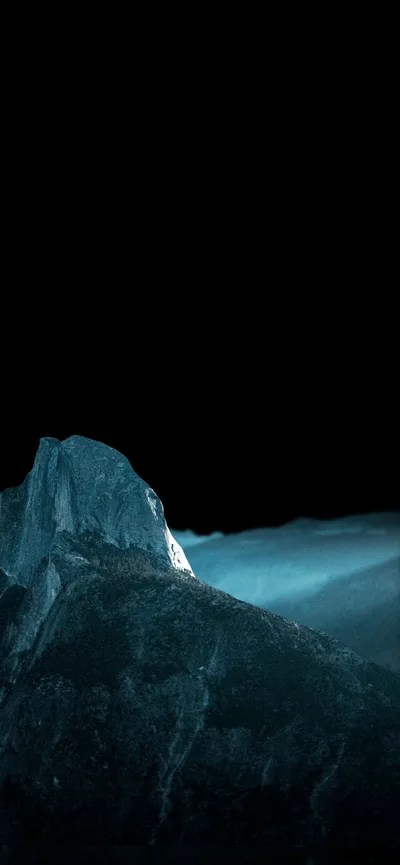 A pale granite outcrop catches cold light on the left while blue mist rolls behind it, the whole upper half kept black.