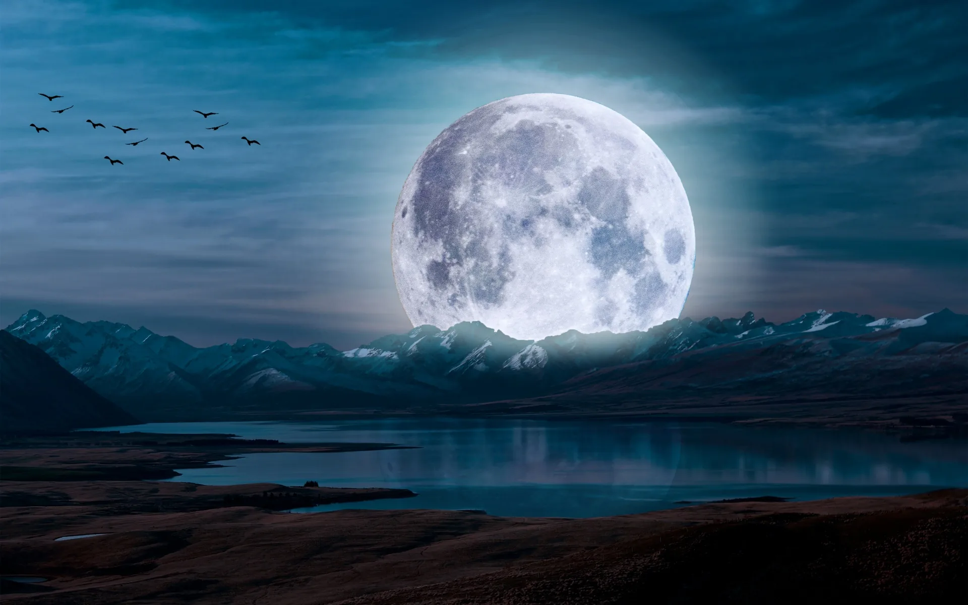 An oversized moon rises behind snow-capped peaks and a still lake, a line of birds crossing the upper left corner of the teal sky.