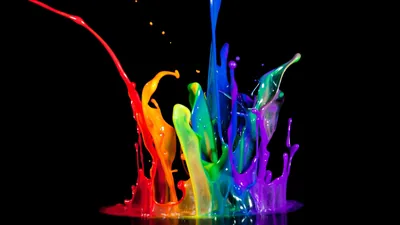 Streams of paint in every colour collide and leap upward against a solid black background.