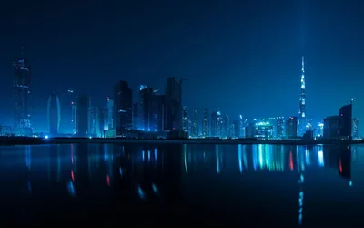 The Burj Khalifa fires a light beam into a teal night sky while the whole skyline doubles itself in the still water filling the lower half.