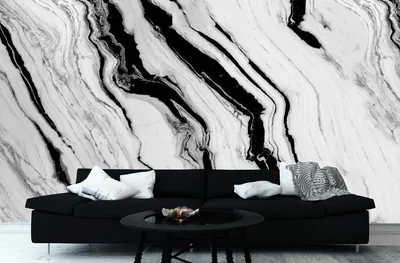 A living room wall covered in swirling black and white marble ink, a dark sofa and round coffee table set in front of it.
