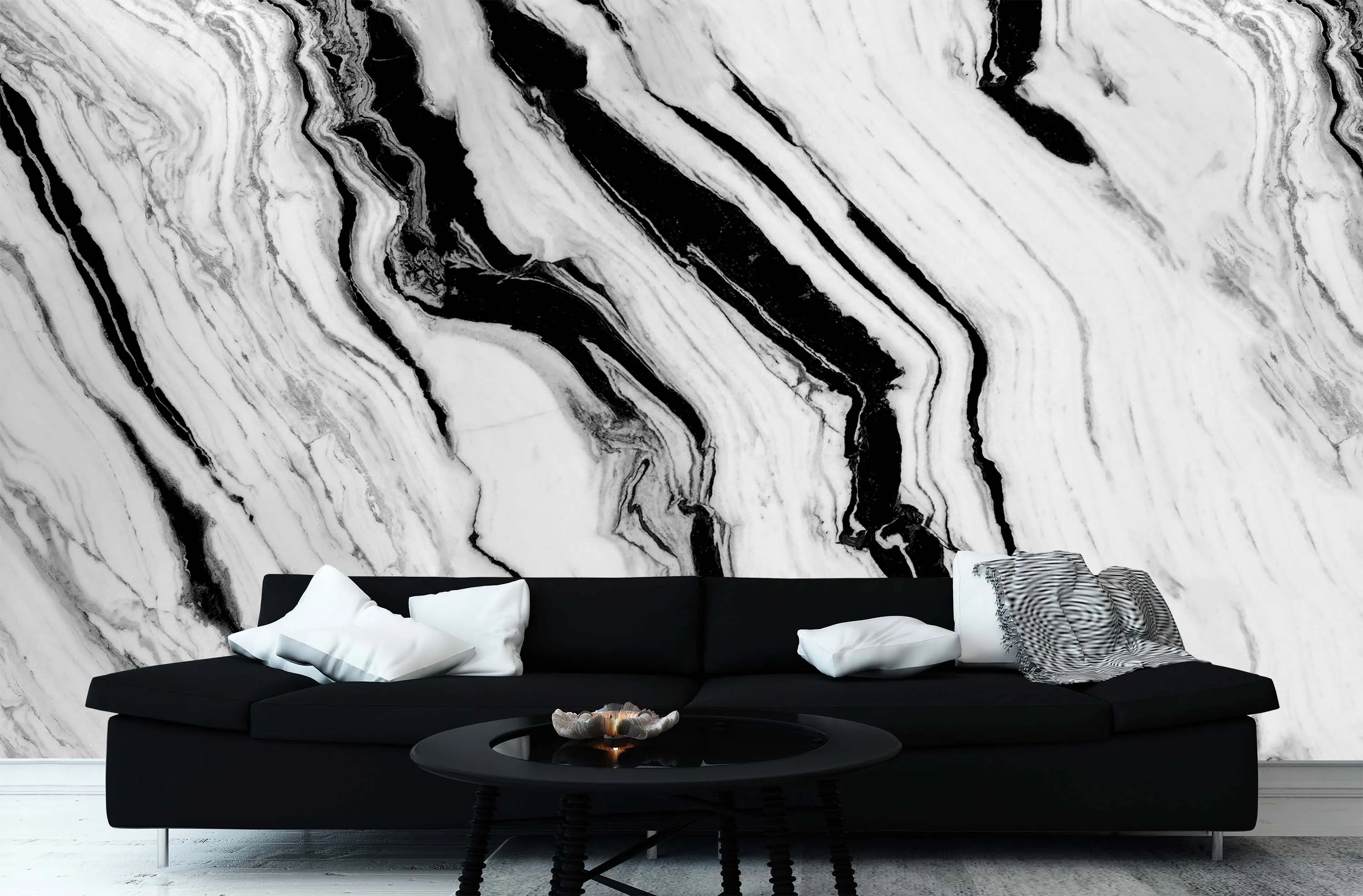A living room wall covered in swirling black and white marble ink, a dark sofa and round coffee table set in front of it.