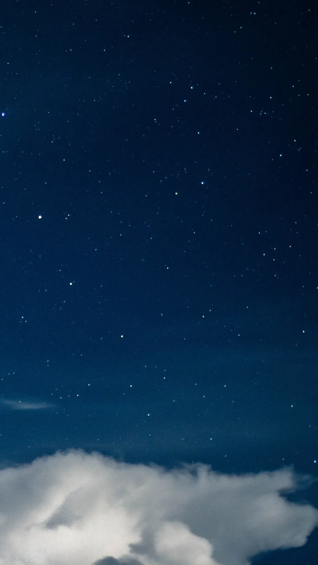 Scattered stars on a navy sky with a bank of white cloud rising from the bottom edge — the upper two thirds stay dark and uncluttered.