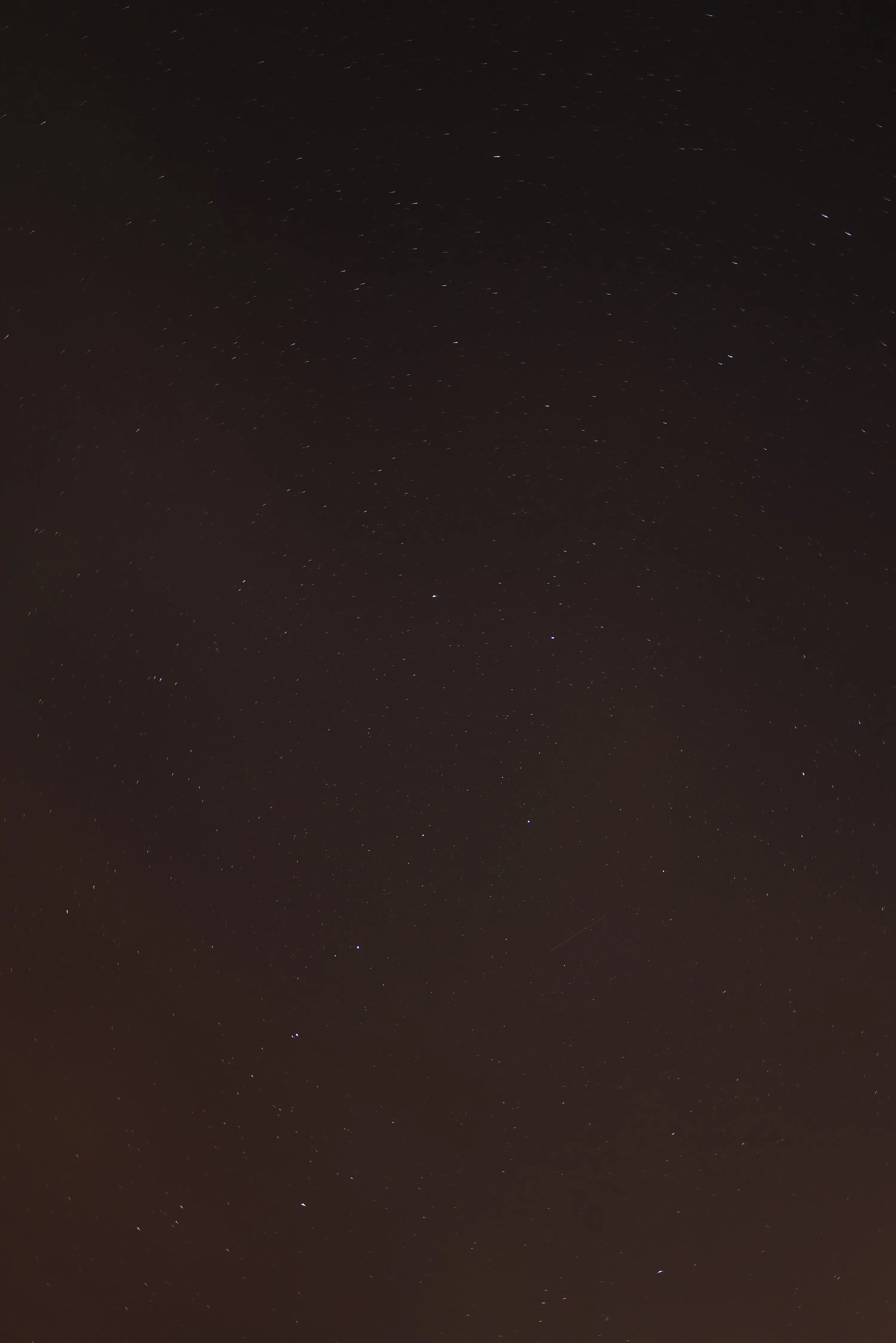 A near-empty sky in dark brown-black, only a scattering of dim stars visible — almost the whole frame is clear space.