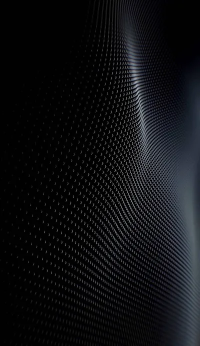 A dotted carbon surface ripples down this tall frame, highlights tracing the curves on the right while the left edge stays pure black for OLED.